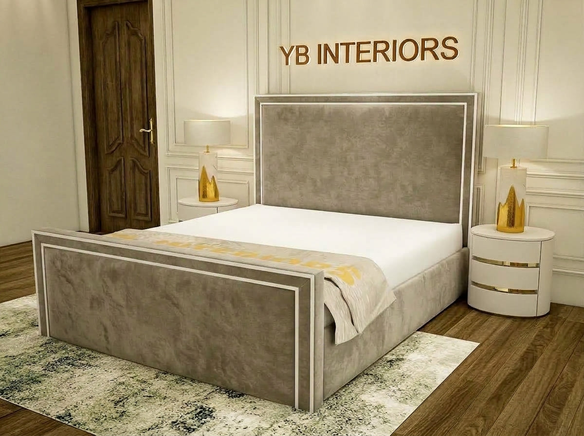A modern upholstered bed frame in taupe with white trim, shown in a styled bedroom setting with matching nightstands, lamps, wood flooring, and a rug. The wall above features the text 'YB INTERIORS'.
