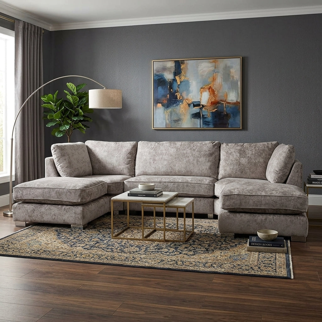 A modern sectional sofa upholstered in textured taupe fabric, styled in a contemporary living room with a patterned area rug, gold coffee table, and a dark gray wall featuring an abstract painting.