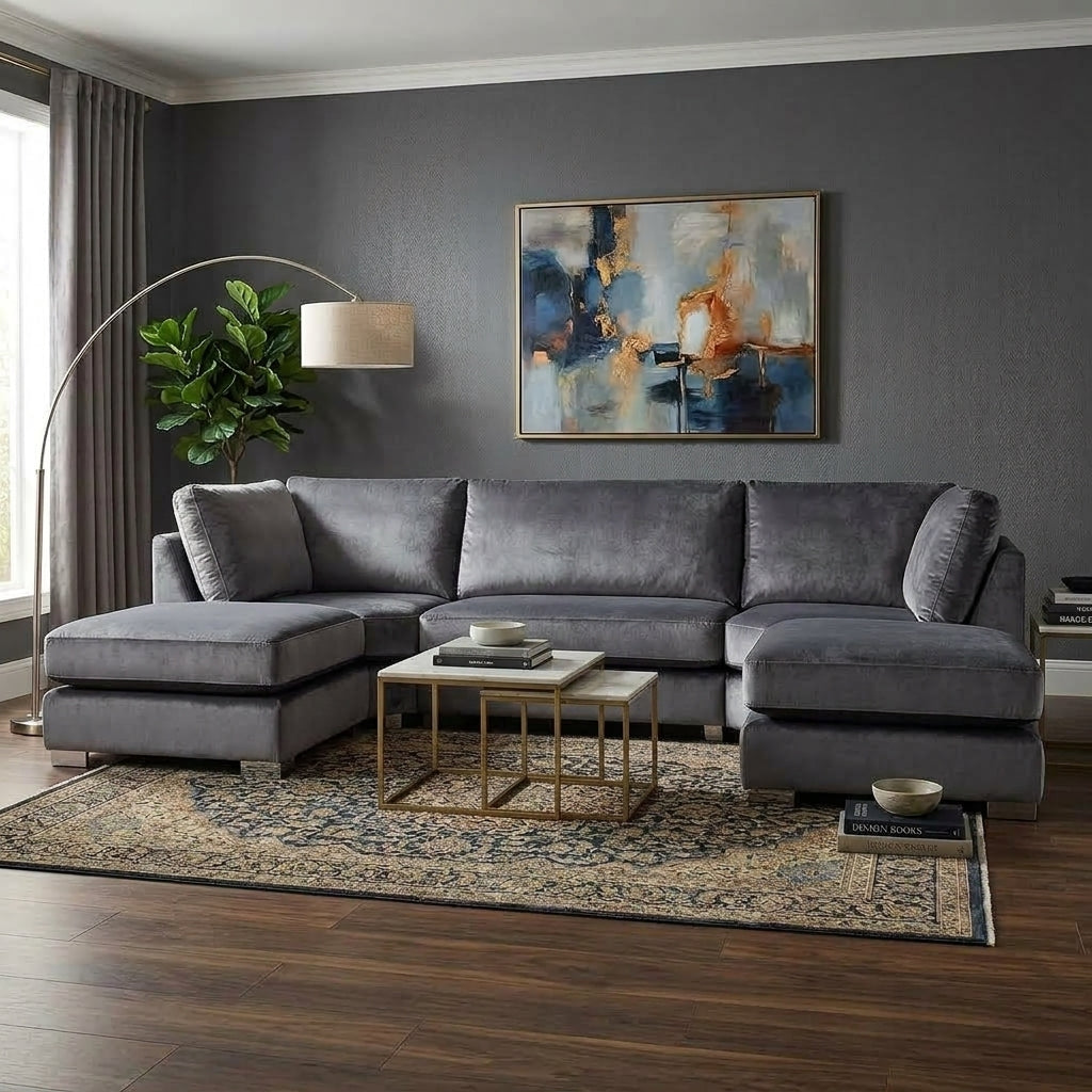 A gray fabric sectional sofa with a left-facing chaise and right-facing chaise, styled in a modern living room with a patterned area rug, gold coffee table, and a large abstract painting on the gray wall.
