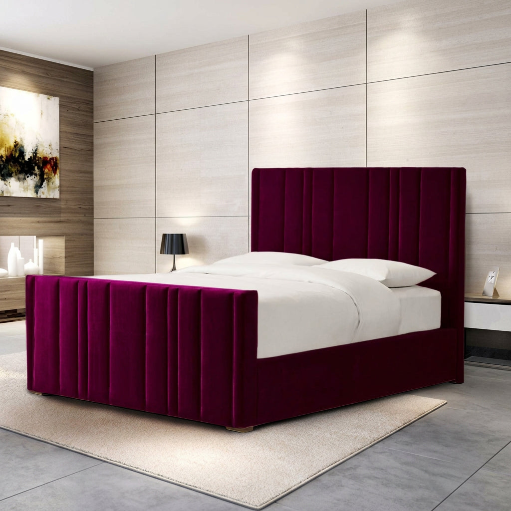 A modern bed with a tall, channel-tufted headboard and matching footboard in deep magenta velvet, dressed in white bedding, set in a contemporary bedroom with light wood paneled walls.