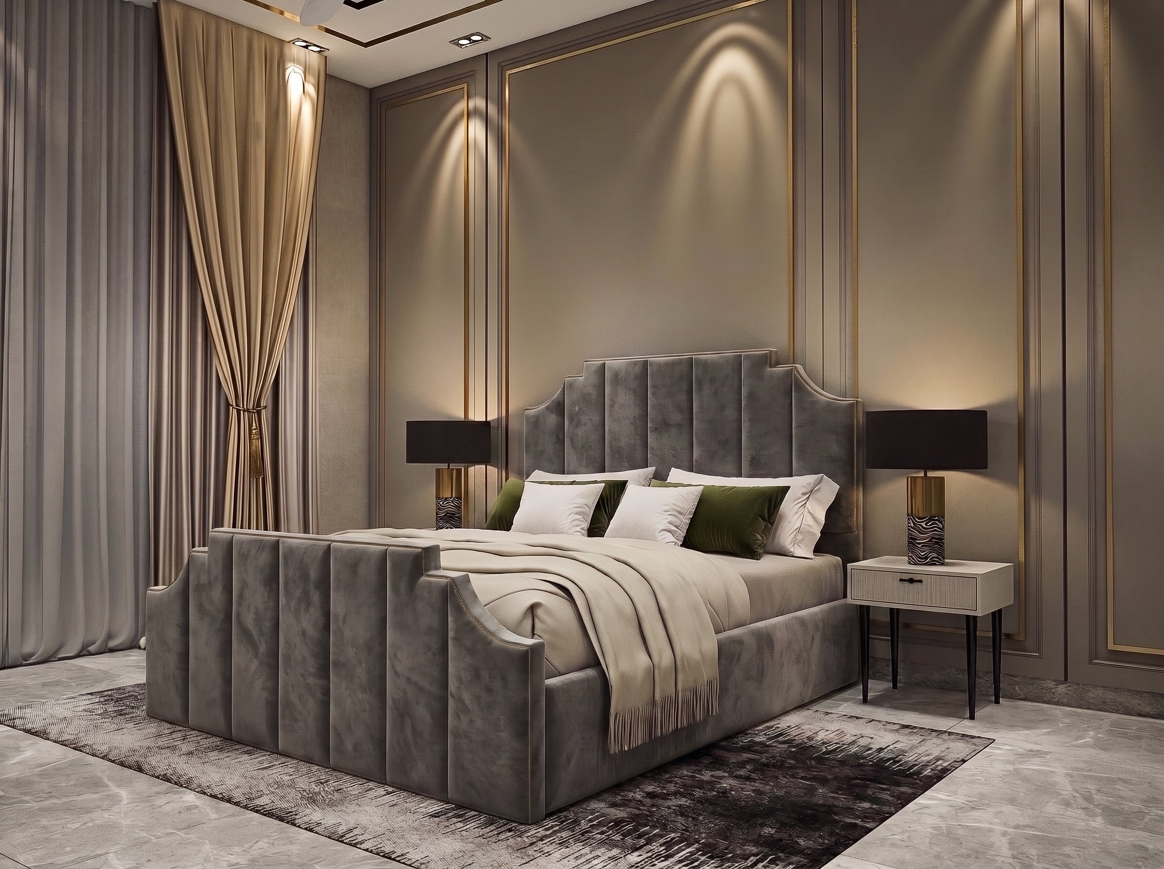 A luxury bedroom featuring a high, tufted gray velvet bed frame with matching headboard and footboard, styled with neutral bedding, green accent pillows, and flanked by two bedside tables with black lamps against a beige paneled wall with gold trim.